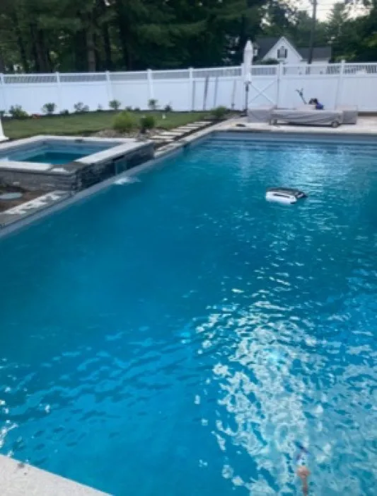 Clear backyard pool with an automatic pool cleaner running