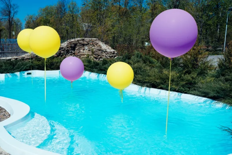 Colorful balloons floating in a clean, clear swimming pool