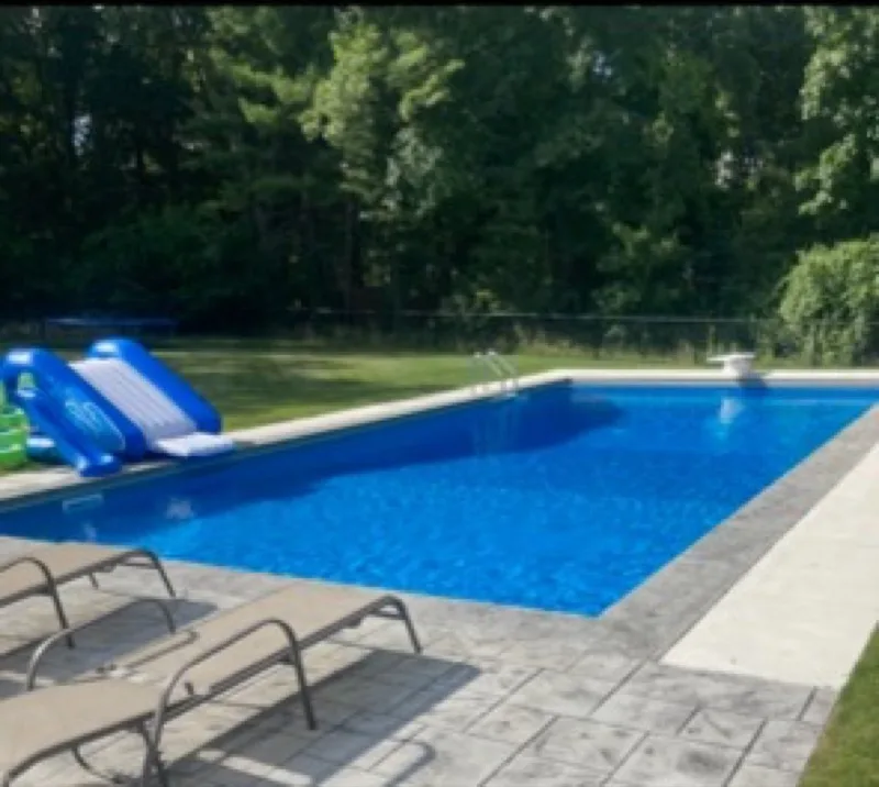 A well-maintained backyard pool with a water slide, ready for the season